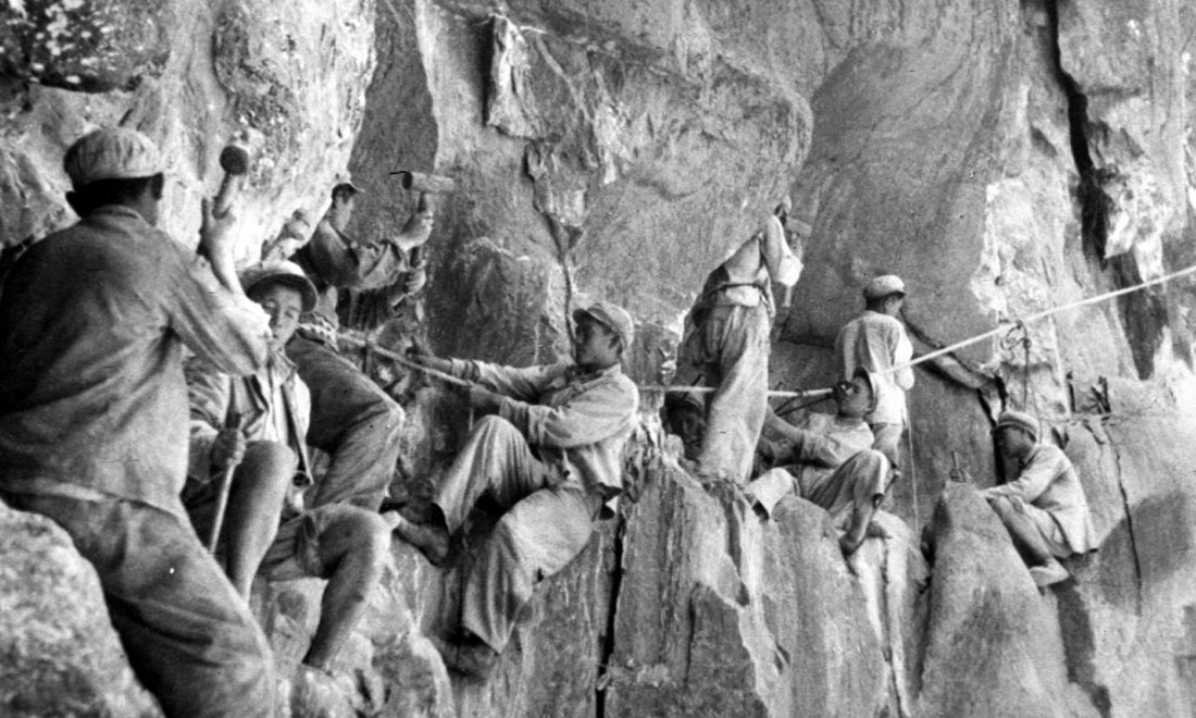 1954年，修筑康藏公路的解放軍戰(zhàn)士們在怒江兩岸的懸崖陡壁上辟山筑路。新華社稿 李萬春、張加里攝